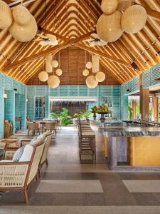 a restaurant with wooden ceilings and chairs and a bar at JOALI Maldives in Raa Atoll