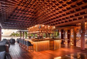 a restaurant with a bar with chairs and a wooden ceiling at JOALI, Maldives in Raa Atoll