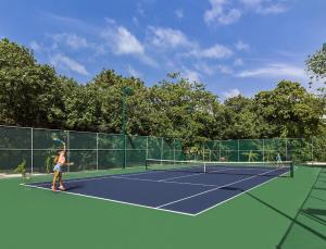 two people playing tennis on a tennis court at JOALI, Maldives in Raa Atoll