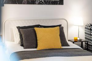 - une chambre avec un lit blanc et un oreiller jaune dans l'établissement Apartments Wilcza 55 by Renters, à Varsovie