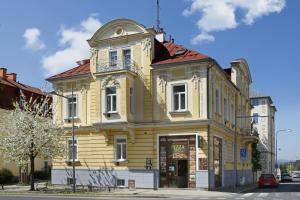 a yellow building with a balcony on a street at Homely Apartments Villa Christiana in Mariánské Lázně