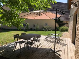 uma mesa e cadeiras e um guarda-sol num deque em La Grange aux Ecureuils em Levernois