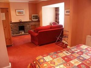 een woonkamer met een rode bank en een open haard bij The Blacksmiths Arms in Brampton