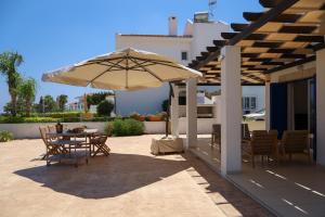 un patio avec une table et un parasol dans l'établissement Phaedrus Living: Seaside Luxury Villa Anafi, à Paralímni