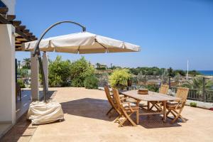 un patio avec une table et un parasol dans l'établissement Phaedrus Living: Seaside Luxury Villa Anafi, à Paralímni