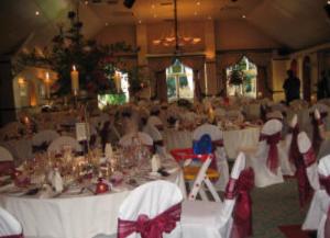 a banquet hall with white tables and chairs with bows at The oaklands hotel in Weaverham