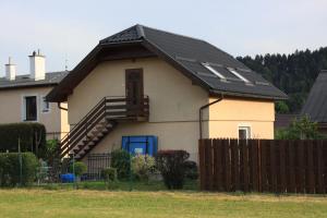 a house with a black roof and a fence at Apartmán pod Černou horou in Rožnov pod Radhoštěm