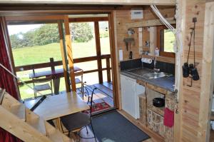 a kitchen and dining room in a tiny house at Cabane des Guernazelles in Valderoure +21 photos