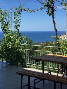 un banco de madera en la parte superior de un balcón con vistas al océano en Chaika Guest House, en Tuapse