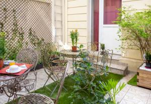 eine Außenterrasse mit Stühlen, Tischen und Pflanzen in der Unterkunft Hôtel Montsouris Orléans in Paris