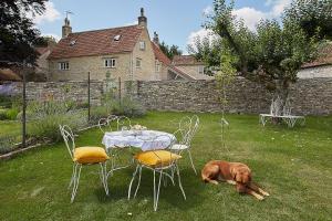 un cane steso sull'erba accanto a un tavolo e sedie di Cherry tree farm B and B a Frome