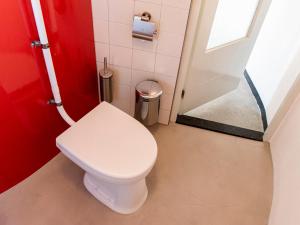 bagno con servizi igienici bianchi e parete rossa. di SWEETS - Kortjewantsbrug ad Amsterdam