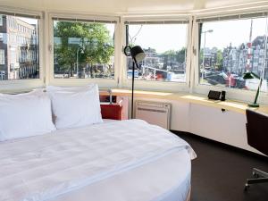 a bedroom with a bed and a desk with windows at SWEETS - Kortjewantsbrug in Amsterdam
