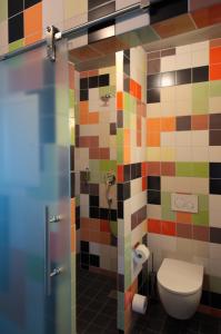 a bathroom with a toilet and a colorful tiled wall at elferrooms Hotel in Ubstadt-Weiher