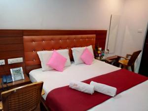 a bedroom with a bed with pink and white pillows at Medavakkam Sri Sai Residency in Chennai