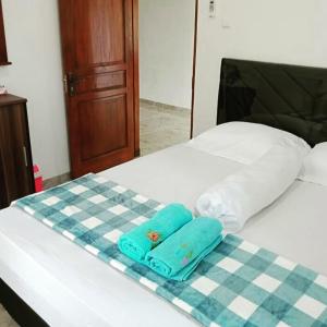 a bed with a checkered blanket and two towels on it at ZG Homestay Solo in Sumber
