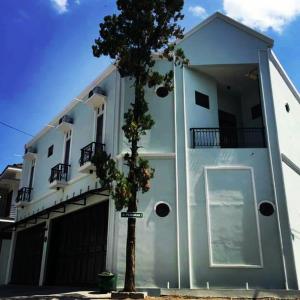 a white building with a tree in front of it at ZG Homestay Solo in Sumber