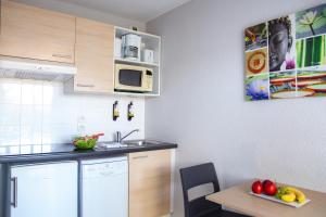 a small kitchen with a table and a microwave at Zenitude Hôtel-Résidences La Tour de Mare in Fréjus