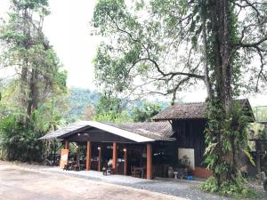 a building with a table and chairs in front of it at Suan Rom Mai Chanthaburi สวนร่มไม้ จันทบุรี in Khlung