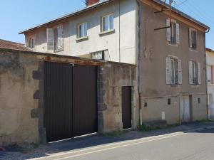 an old building with two garage doors next to a street at Chez Stéphane et Patricia in Vertaizon