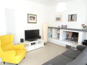 a living room with a yellow chair and a television at Italy Home in San Costanzo