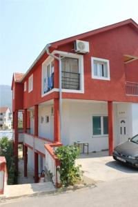 a red house with a car parked in front of it at Apartments Bordo in Tivat