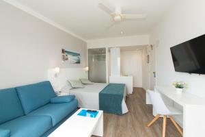 sala de estar con sofá azul y cama en Hotel Pinos Playa, en Cala Santanyi