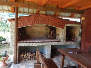 a brick fireplace with a table and a wooden roof at Apartments Nena in Smoljanac