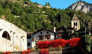 a building with red flowers in front of a mountain at Chalet Monte Nebius in Vinadio