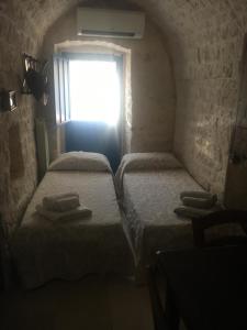 2 camas individuales en una habitación con ventana en Masseria Oreglia, en Ceglie Messapica