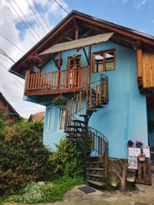a blue house with a staircase and a balcony at Eszter Panzió in Praid