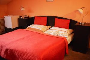 a bedroom with a bed with red sheets and pillows at Penzion Tilia in Levice