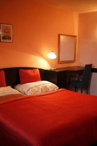 ein Hotelzimmer mit einem roten Bett und einem Schreibtisch in der Unterkunft Penzion Tilia in Levice