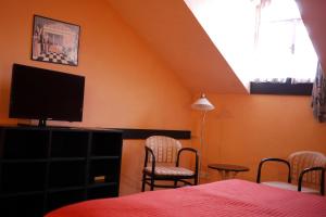 a bedroom with a bed and a tv and chairs at Penzion Tilia in Levice