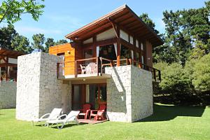a house with chairs and a balcony on the grass at Cabañas San Dionisio in Mar de las Pampas