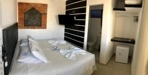 1 dormitorio con cama blanca y almohadas blancas en Pousada Kepha, en Guarujá