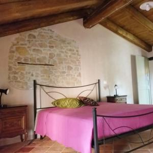 Cama rosa en habitación con pared de piedra en Langa 4 Love, en Novello