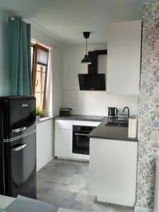 una cucina con armadietti bianchi e frigorifero nero di Apartament Kopa a Karpacz
