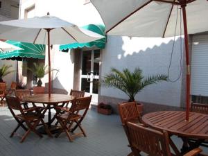 2 Tische und Stühle mit Sonnenschirmen auf einer Terrasse in der Unterkunft Hotel Rias Baixas in Sanxenxo