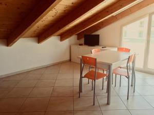 a dining room with a white table and orange chairs at Residence Levante in Misano Adriatico