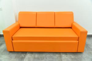 an orange couch sitting next to a wall at Happy Home in Bhuj