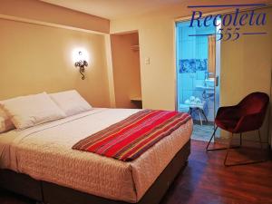een slaapkamer met een bed en een rode stoel bij Casa Durand in Cuzco