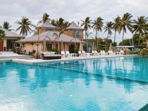 a large swimming pool with white chairs and palm trees at Seaman Resort in Haad Chao Samran