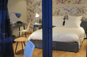 1 dormitorio con cama, mesa y escritorio en Hôtel-Restaurant L'Aquarelle, en Breuillet