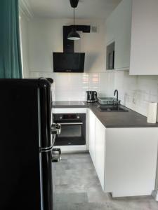 una cucina con armadietti bianchi e frigorifero nero di Apartament Kopa a Karpacz