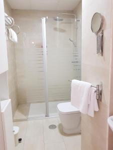 uma casa de banho branca com um chuveiro e um WC. em Lolita's house Alhambra em Sevilha