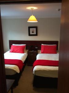 a hotel room with two beds with red pillows at The Stag Hotel in Banchory