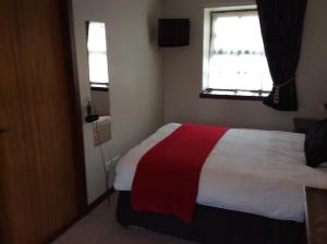 een slaapkamer met een bed met een rode en witte deken bij The Stag Hotel in Banchory