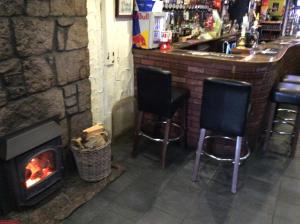a bar with two black chairs and a fireplace at The Stag Hotel in Banchory