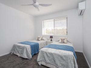 2 camas en una habitación con paredes blancas y ventana en Beerburrum St 2 22 Dicky Beach en Caloundra